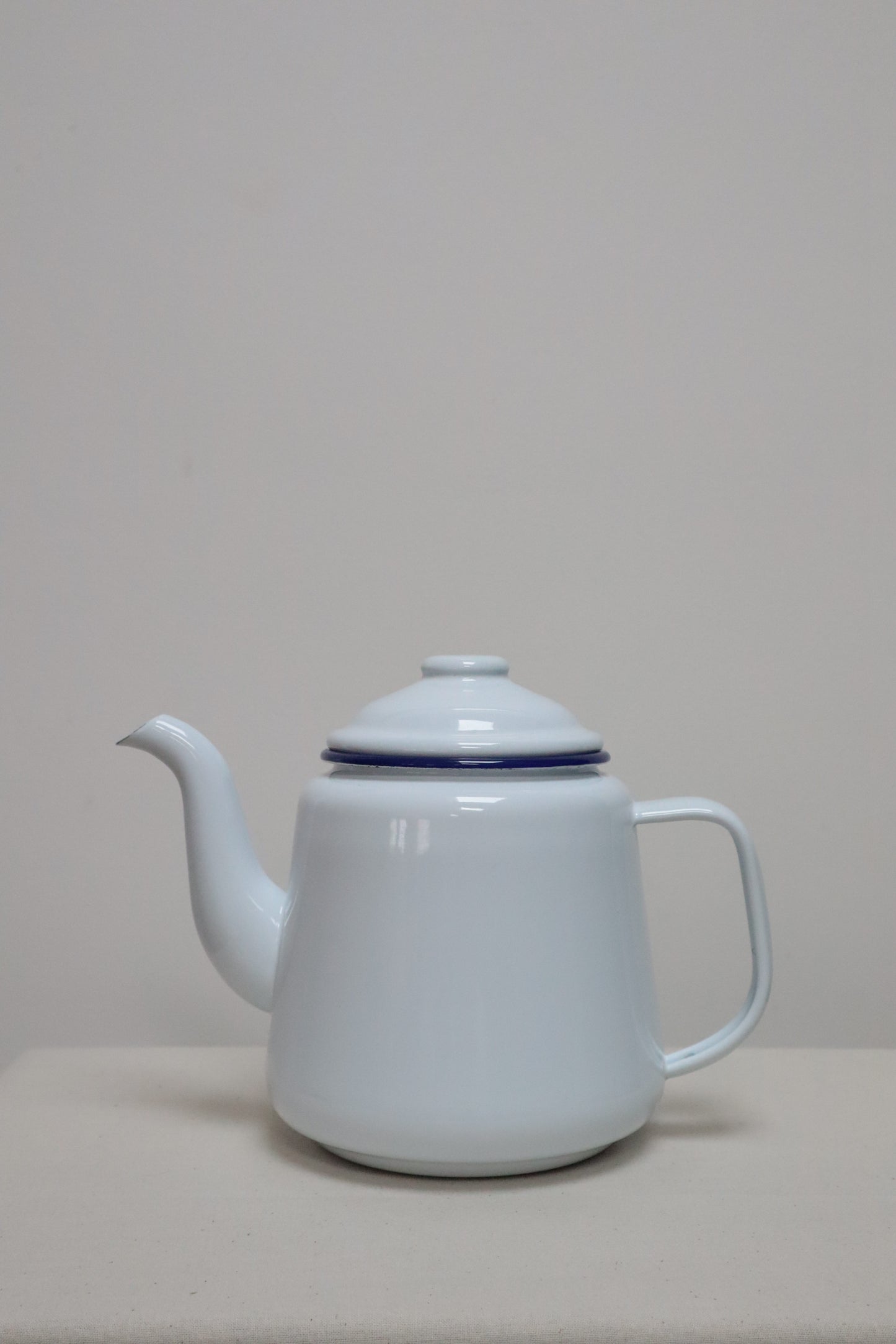 Vintage white enamel teapot with blue rim