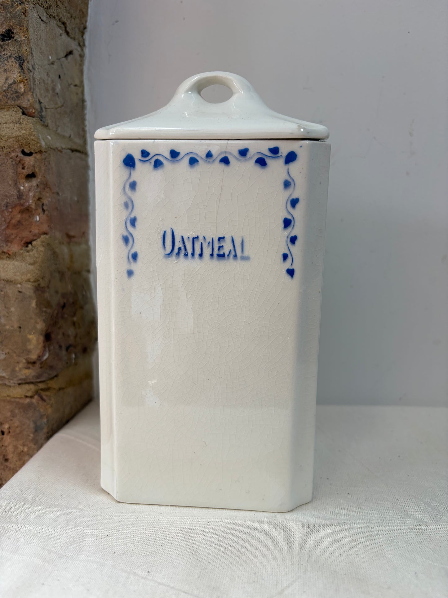 A pair of white kitchen storage jars with blue decorative borders and labels reading 'OATMEAL' and 'FLOUR'.