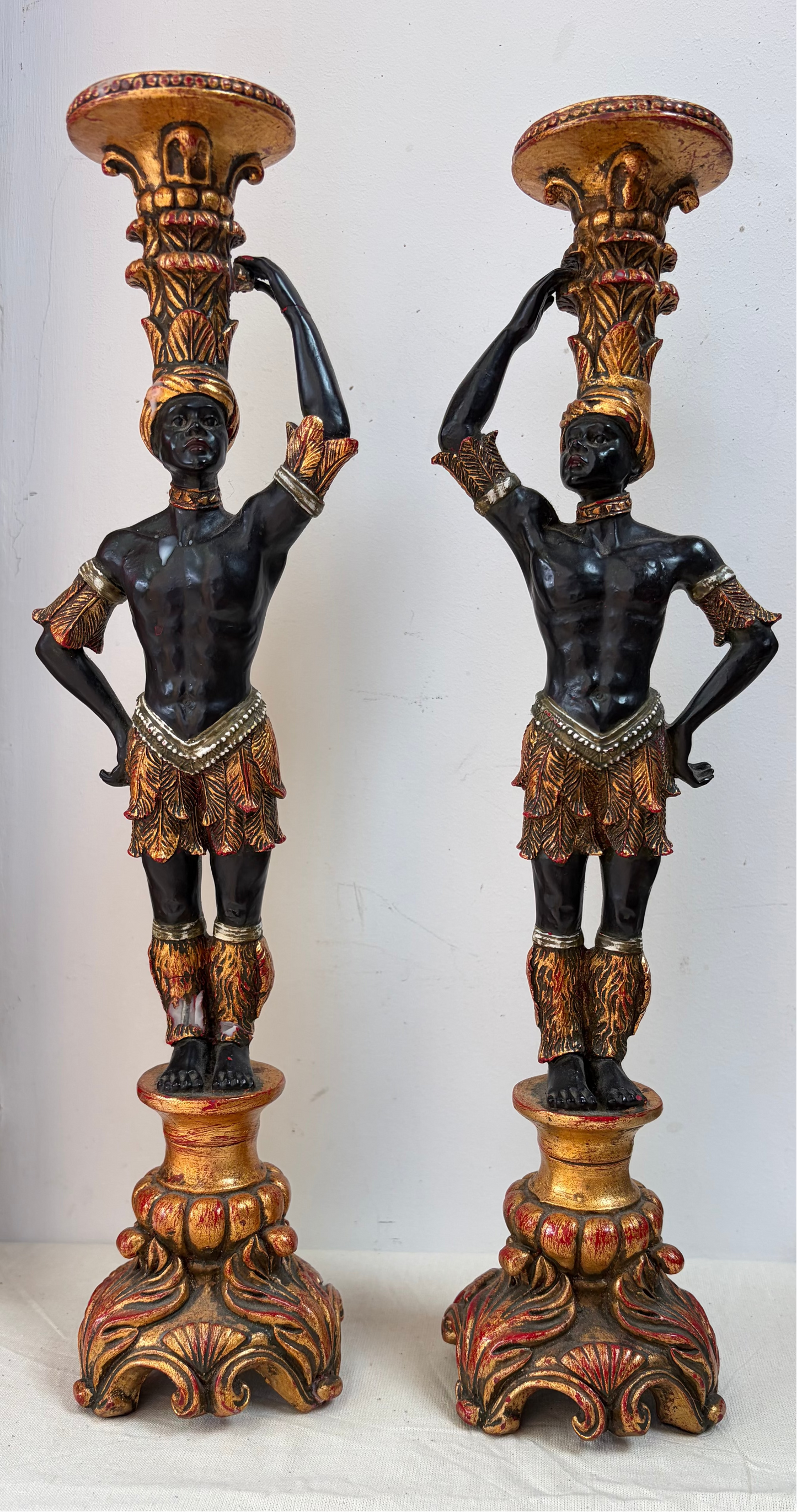 A pair of ornate decorative candlesticks featuring figures with gilded gold and bronze detailing.