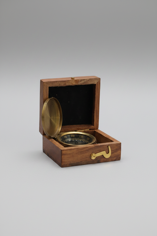 Brass compass in a wooden box on a reflective surface with a blurred background