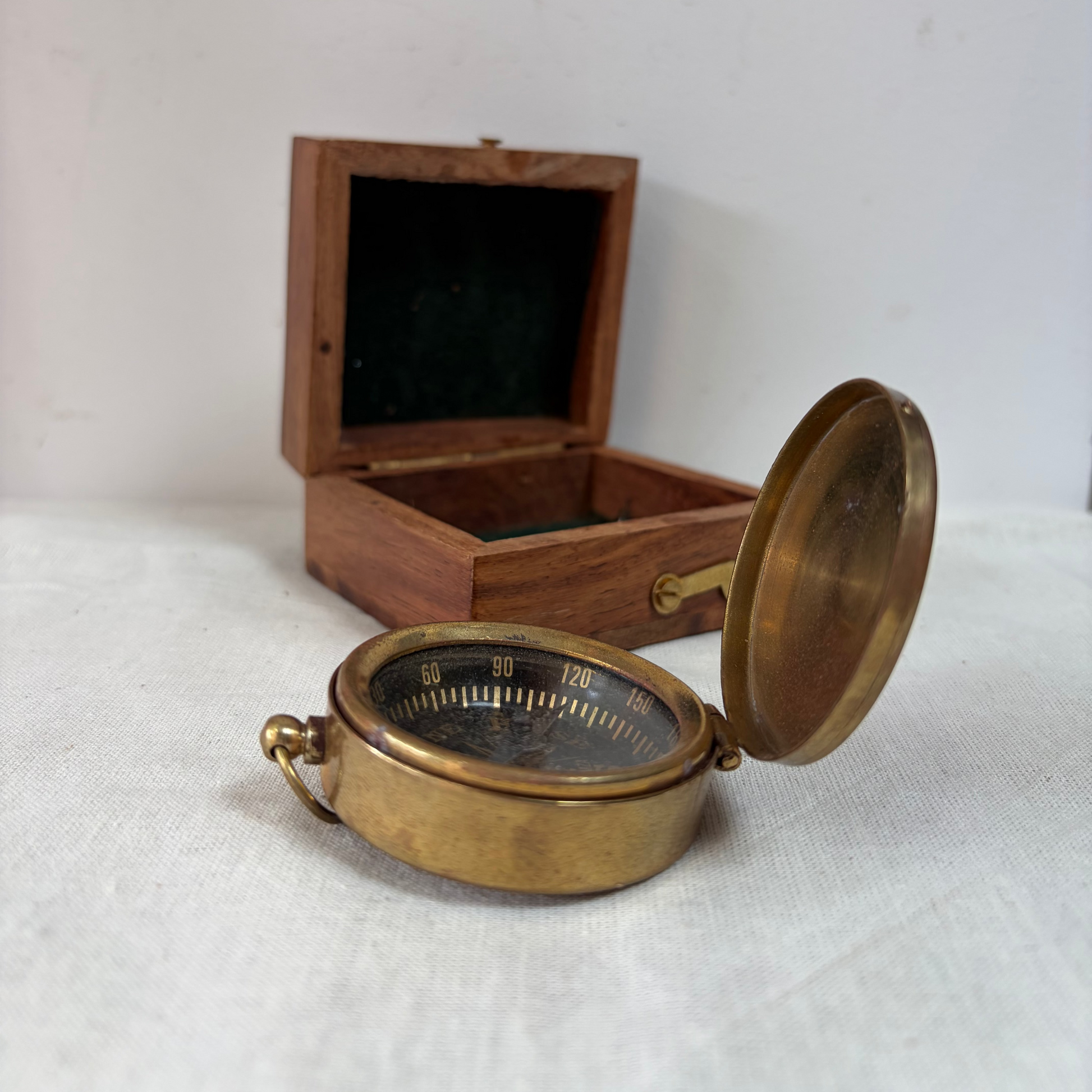 A small round brass pocket compass in a wooden presentation box.