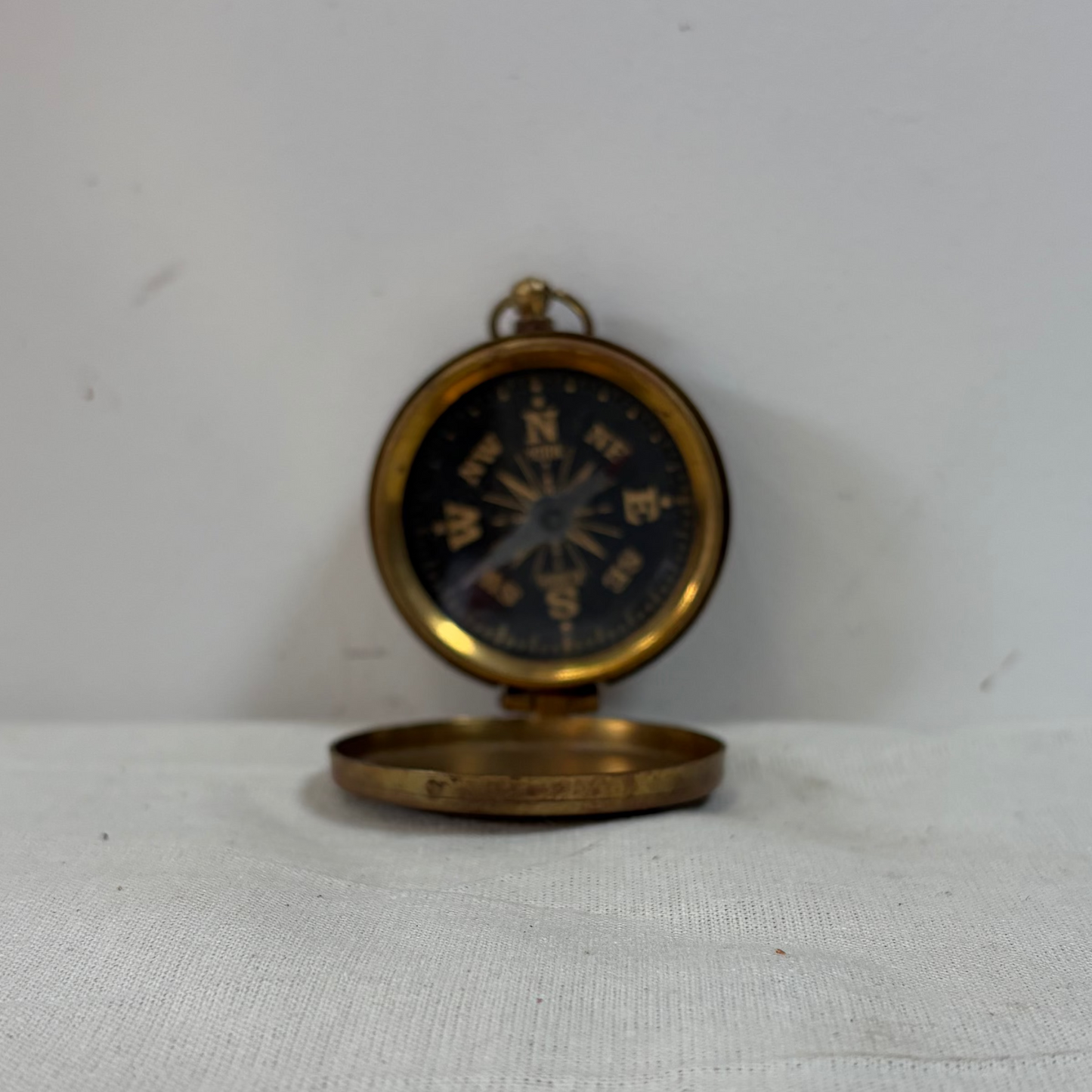 A small round brass pocket compass in a wooden presentation box.